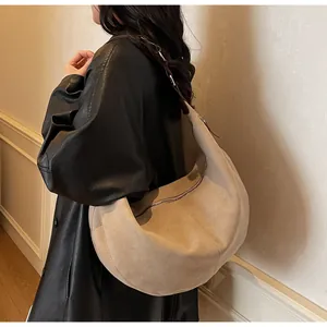 Dettaglio di una grande borsa hobo in camoscio beige con zip e cuciture a vista