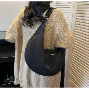 Dettaglio borsa tote a mezzaluna in camoscio nero con texture opaca e design ampio a spalla