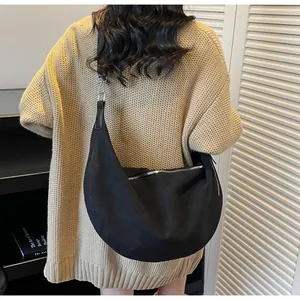 Dettaglio della borsa hobo in camoscio nero con cerniera argentata e ampia tracolla regolabile