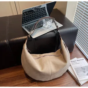 Dettaglio borsa hobo in camoscio su sedia con laptop che mostra trama e scena da ufficio