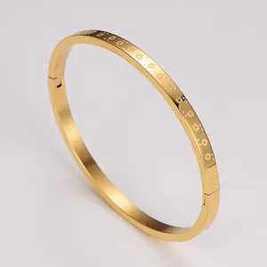 Gros plan d'un bracelet jonc en acier doré avec motifs de flocons de neige gravés