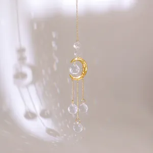 Golden suncatcher with crescent moon face and hanging multifaceted crystal prisms
