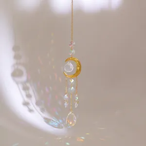 Detail of golden moon suncatcher with crystal prisms reflecting rainbow light spots