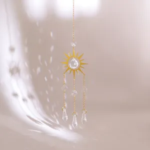 Detail of golden sunburst suncatcher with faceted crystal drop and light reflection