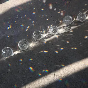 Prismes en cristal K9 à facettes créant des arcs-en-ciel sur un sol gris au soleil