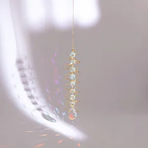 Detail of golden spiral stabilizer suncatcher with light cyan crystal beads and prism light