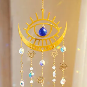 Close-up of golden suncatcher with crescent moon, blue crystal and rainbow light spots