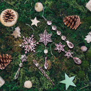 Detailed close-up of pink acrylic snowflake and icicle ornaments on green moss background