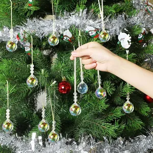 Faceted crystal ball pendant with gold string hanging on a decorated Christmas tree