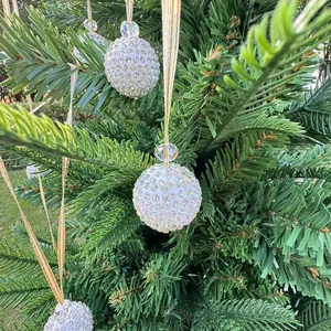 Detailed view of white rhinestone-encrusted Christmas balls hanging on pine branches