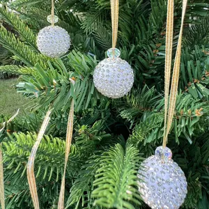 Detailed view of white rhinestone-encrusted Christmas bauble hanging on green pine tree