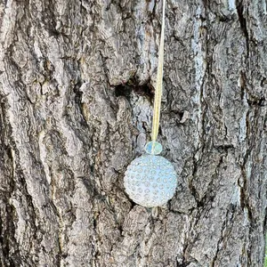 Detail of sparkling crystal rhinestone Christmas ball ornament hanging on a rustic tree branch