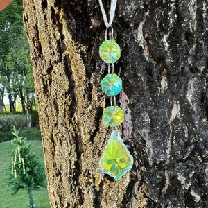 Detail of aurora crystal suncatcher with teardrop prism hanging on a tree branch