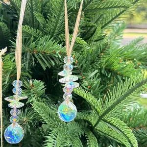 Detail of crystal suncatcher with iridescent faceted ball hanging on a green pine branch