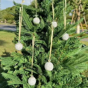 Close-up of sparkling crystal disco ball ornaments hanging on a green pine tree branch