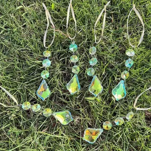 Detailed view of 6-piece aurora crystal suncatchers refracting light on green grass