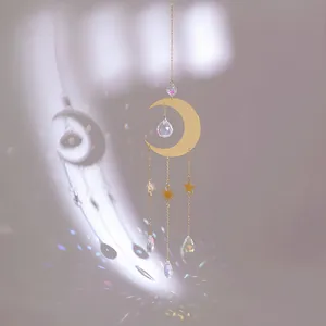 Golden moon suncatcher with crystal prisms and stars reflecting rainbow light on purple wall