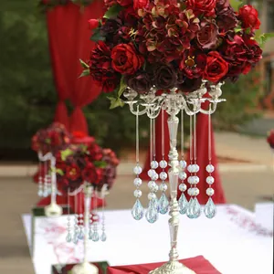 Detalle de prismas de cristal colgando de un soporte plateado con rosas rojas