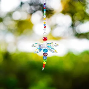 Close-up of dragonfly suncatcher with colorful crystal beads and bokeh garden background