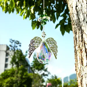 Detail of crystal suncatcher with angel wings hanging from a tree branch in sunlight