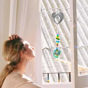 Detail of angel wing suncatcher with heart charm casting rainbows near window