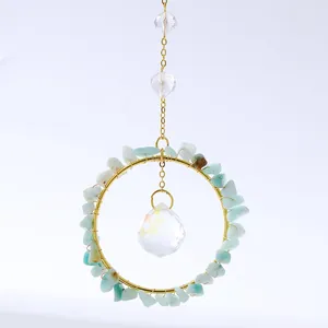 Macro detail of suncatcher showing green crystal stones wrapped on golden metal ring