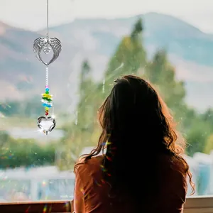 Suncatcher with angel wings and heart crystal hanging in a bright window with mountain view