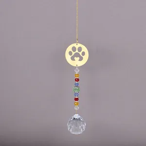 Detail of crystal suncatcher with gold cat paw pendant and colorful beads on gray background