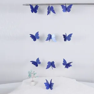 Detalle de guirnaldas de mariposas 3D azules brillantes colgadas en pared blanca