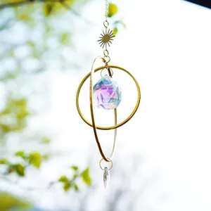 Macro shot of sun and moon crystal suncatcher featuring aurora crystal ball and gold rings