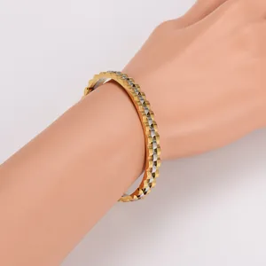 Detail view of gold and silver gear-shaped bangle with wave texture on wrist