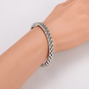 Detailed view of silver gear-textured metal bracelet on wrist with polished finish