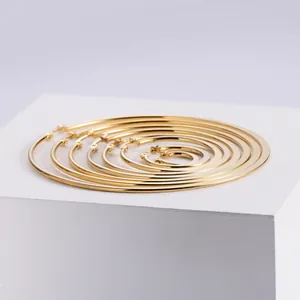 Set of seven assorted sizes of polished gold hoop earrings shown on a white pedestal