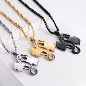 Tres collares con colgante de dragón en plata, oro y negro sobre bloques blancos