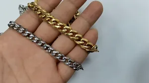 Close-up of classic silver and gold stainless steel Cuban link necklaces held by hand