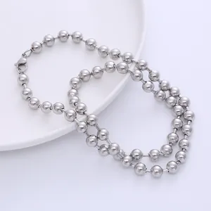 Detail of silver stainless steel ball chain with lobster clasp on ceramic plate