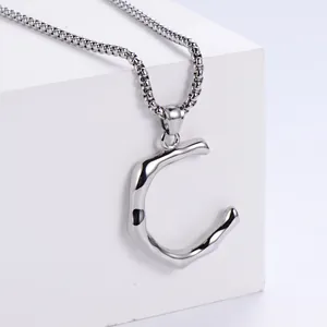 Détail macro du collier en acier inoxydable argenté avec pendentif lettre C texturé