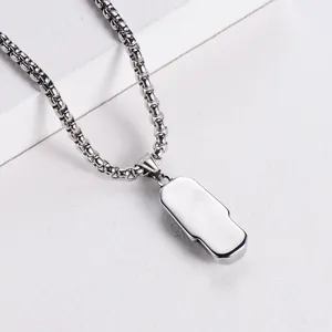 Vue macro du pendentif rectangulaire poli sur une chaîne vénitienne argentée sur blanc