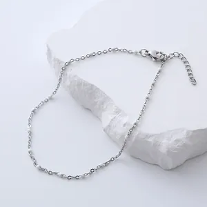 Detailed macro view of silver stainless steel anklet with white beads and lobster clasp