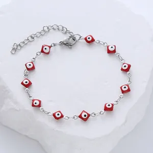 Silver stainless steel bracelet with red square evil eye charms on stone background