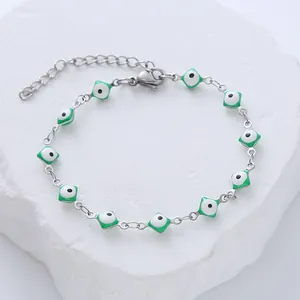 Detailed close-up of a silver stainless steel bracelet with square green evil eye pendants