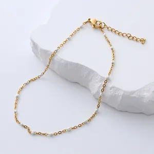 Detail of bohemian gold anklet with white beads, featuring lobster clasp and extension chain