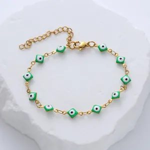 Detailed close-up of gold titanium steel bracelet featuring green evil eye charms