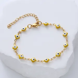 Detailed close-up of yellow evil eye charms on a gold-plated titanium steel bracelet