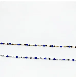 Detail von Gold- und Silberketten mit blau und schwarz emaillierten Olivenanhängern