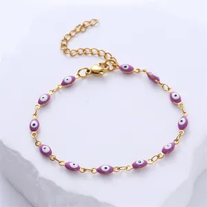 Detail of gold evil eye bracelet featuring purple enamel beads and lobster clasp link