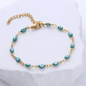 Macro detail of gold-plated evil eye bracelet with blue enamel beads on a stone surface