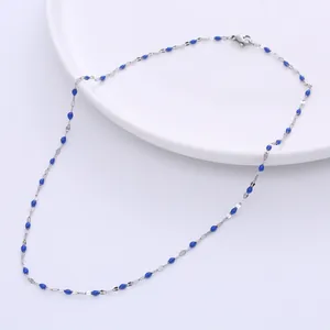 Detail der blauen Perlenkette mit silbernen Metallgliedern und Karabiner auf weißem Teller