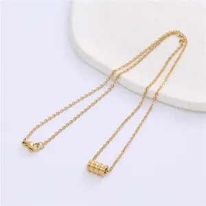 Detail of gold-plated cylinder pendant necklace with delicate chain and lobster clasp