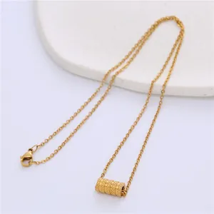 Macro view of gold stainless steel cylinder pendant with engraved diamond texture on O-chain